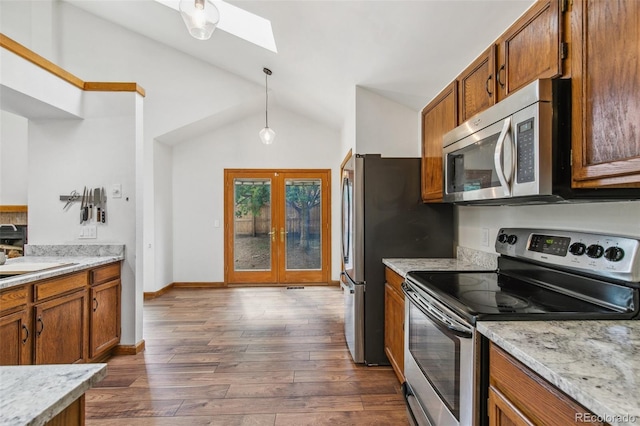 6980 Native Cir, Colorado Springs, CO 80919 - kitchen featuring appliances with stainless steel finishes, a skylight, lofted ceiling, brown cabinets, and dark wood-style flooring