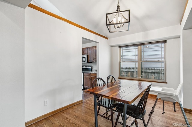6980 Native Cir, Colorado Springs, CO 80919 - dining area featuring a chandelier, vaulted ceiling, baseboards, and wood finished floors