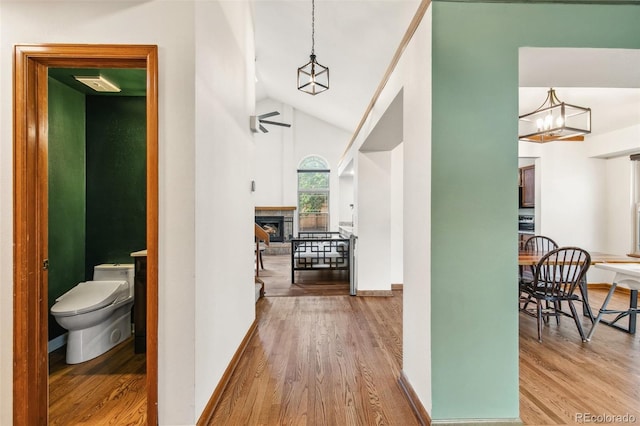 6980 Native Cir, Colorado Springs, CO 80919 - hall with wood finished floors, vaulted ceiling, a chandelier, and baseboards