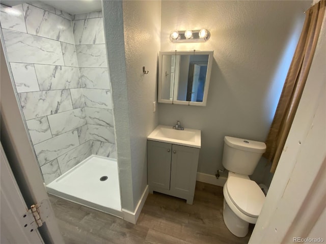 7079 Estes Dr, Arvada, CO 80004 - full bath with toilet, wood finished floors, vanity, a tile shower, and baseboards