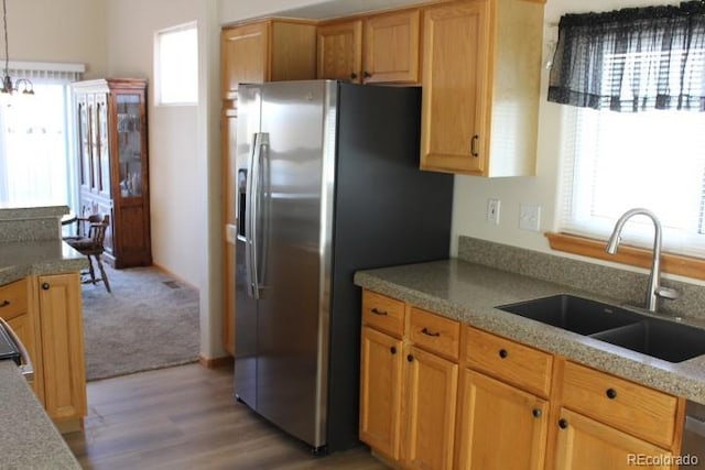 kitchen with stainless steel refrigerator with ice dispenser, sink, decorative light fixtures, and light wood-type flooring