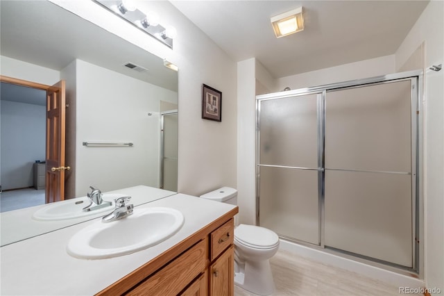 bathroom featuring a shower with shower door, vanity, and toilet