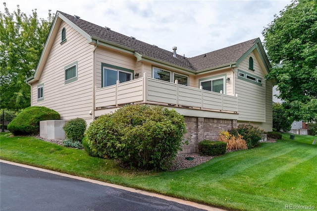 view of property exterior featuring a balcony and a lawn