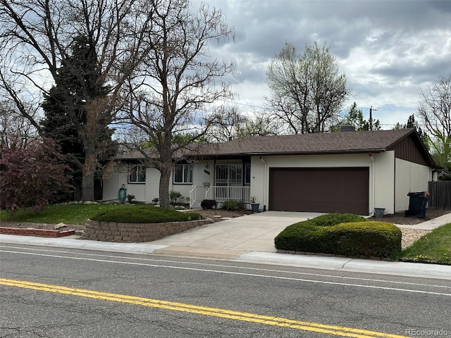 single story home featuring concrete driveway, an attached garage, and a shingled roof