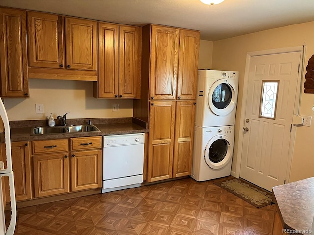 kitchen with white dishwasher, brown cabinetry, stacked washer / drying machine, and a sink