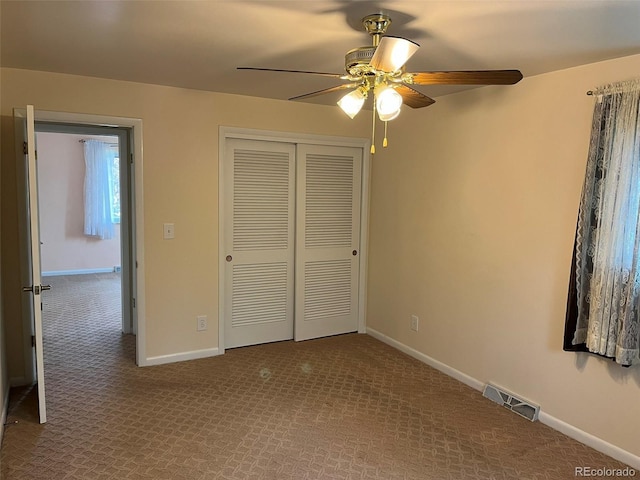 unfurnished bedroom with ceiling fan, visible vents, baseboards, a closet, and carpet flooring