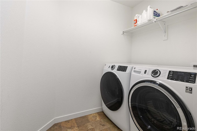 washroom featuring baseboards, laundry area, washing machine and dryer, and stone finish flooring