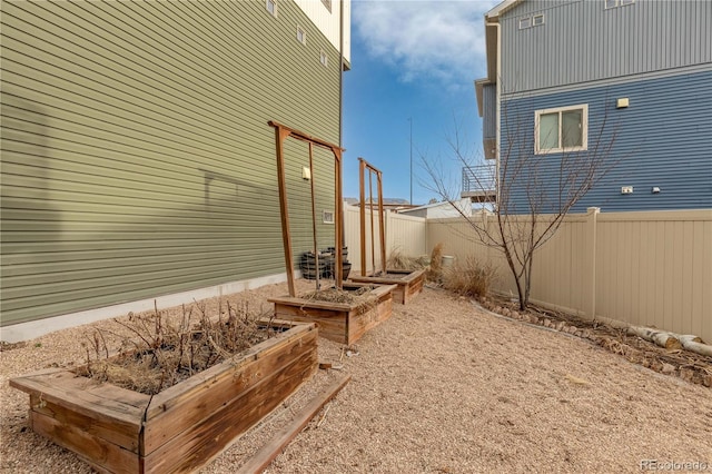 view of property exterior featuring fence and a garden