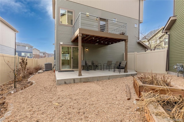 back of house with a fenced backyard, a patio, central AC, and a balcony