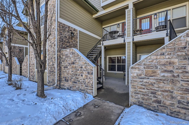 snow covered property entrance with a balcony