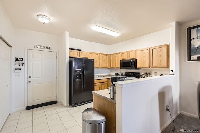 kitchen with light brown cabinets, kitchen peninsula, light tile patterned floors, and black appliances