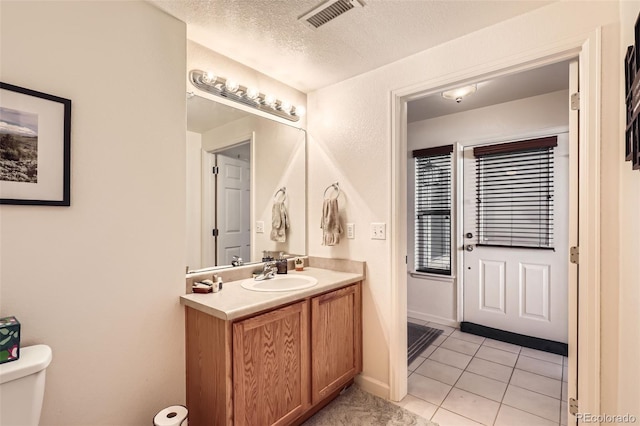 bathroom with tile patterned floors, vanity, toilet, and a textured ceiling