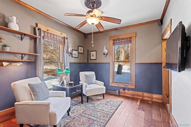 living area with hardwood / wood-style floors, ornamental molding, ceiling fan, and baseboard heating