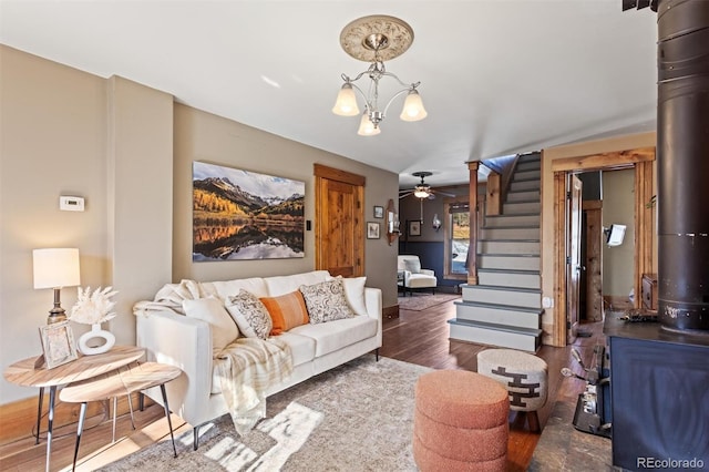 living room with a wood stove, ceiling fan with notable chandelier, and dark hardwood / wood-style floors