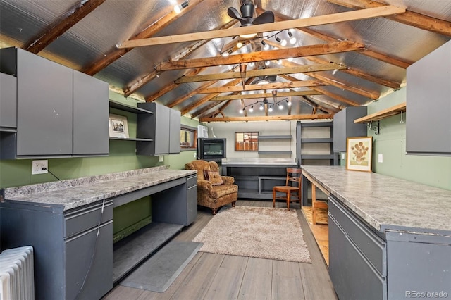 kitchen with ceiling fan, radiator heating unit, lofted ceiling with beams, and light hardwood / wood-style flooring