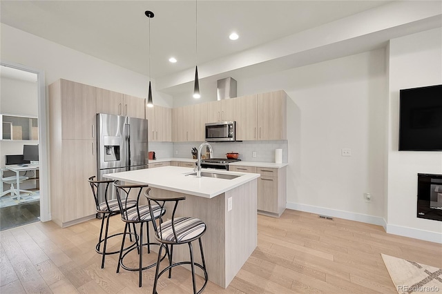 3044 Wilson Ct Unit 2, Denver, CO 80205 - kitchen featuring stainless steel appliances, light brown cabinetry, a breakfast bar area, light wood-style floors, and light countertops