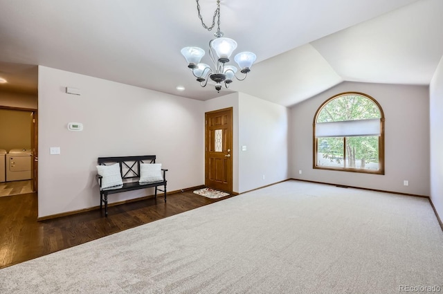 foyer entrance with washing machine and dryer, dark hardwood / wood-style flooring, vaulted ceiling, and a notable chandelier