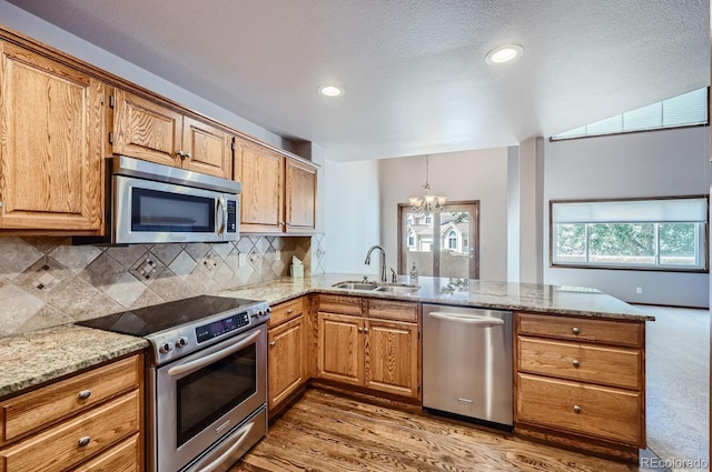 kitchen with sink, a notable chandelier, kitchen peninsula, decorative backsplash, and appliances with stainless steel finishes