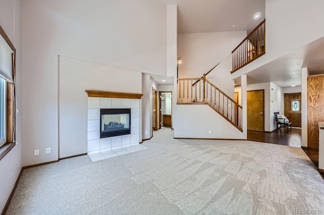 unfurnished living room featuring a towering ceiling, light carpet, and a tile fireplace