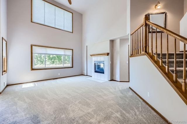 unfurnished living room with a fireplace, light carpet, and a high ceiling