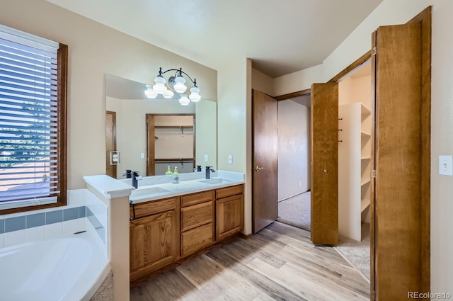 bathroom featuring hardwood / wood-style floors, vanity, a bath, and an inviting chandelier