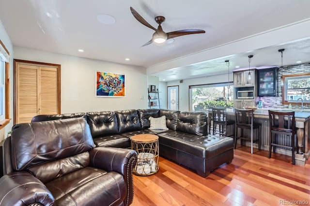 living room with ceiling fan, sink, and hardwood / wood-style flooring