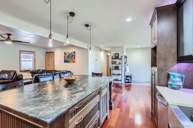 kitchen featuring dark brown cabinetry, ceiling fan, dark wood-type flooring, pendant lighting, and a kitchen island