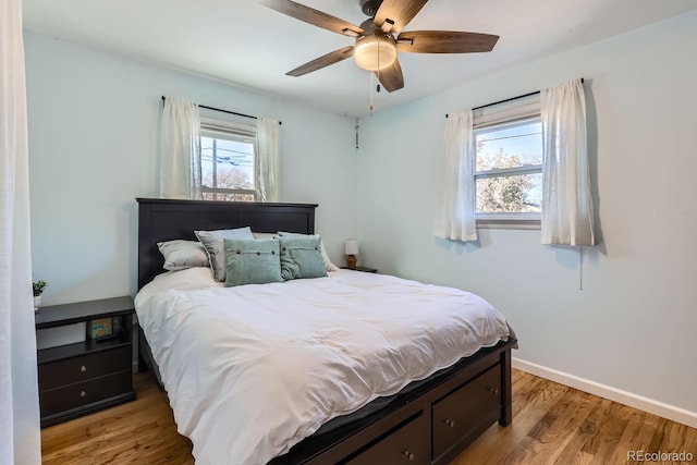 bedroom with ceiling fan, light hardwood / wood-style flooring, and multiple windows