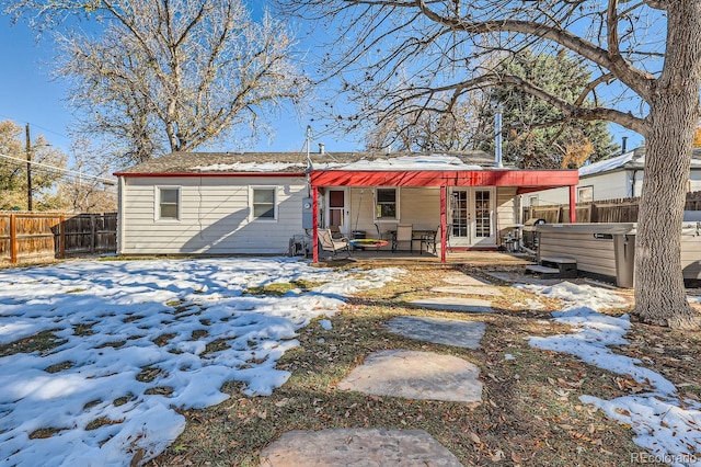 snow covered back of property featuring a hot tub