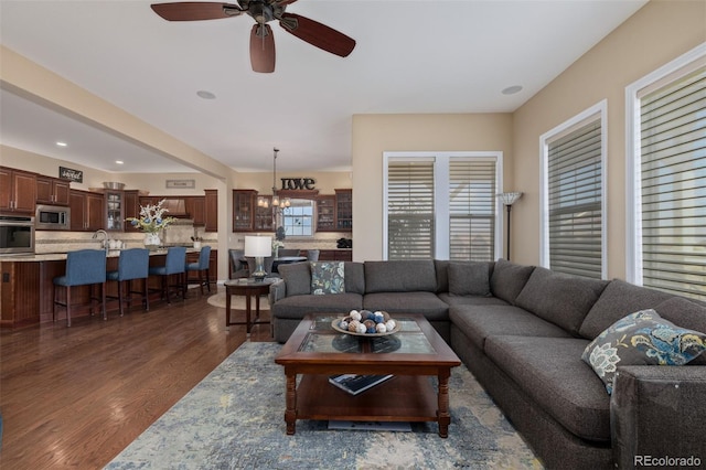 living area featuring recessed lighting, ceiling fan with notable chandelier, and dark wood-style floors
