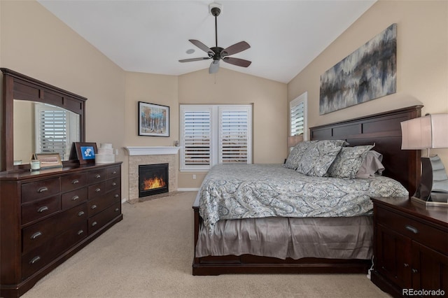 bedroom with light colored carpet, a ceiling fan, vaulted ceiling, and a fireplace with flush hearth