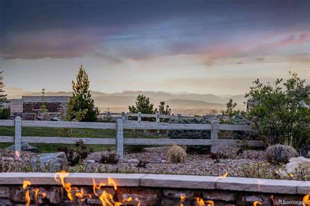 yard at dusk with an outdoor fire pit, fence, and a mountain view