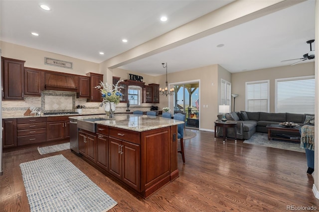 kitchen featuring a kitchen breakfast bar, a center island, tasteful backsplash, dark wood finished floors, and a sink