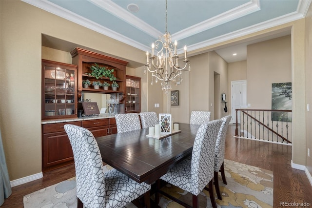 dining area with an inviting chandelier, crown molding, and dark wood-type flooring