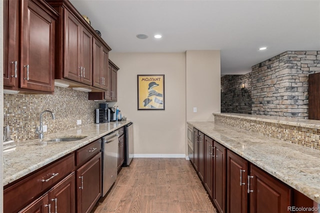 kitchen featuring a sink, light stone counters, decorative backsplash, and stainless steel dishwasher