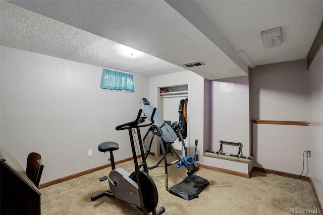 workout room featuring a textured ceiling and light carpet