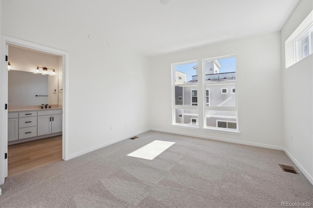 1243 Rhett Dr, Erie, CO 80026 - unfurnished bedroom with baseboards, light carpet, visible vents, and a sink