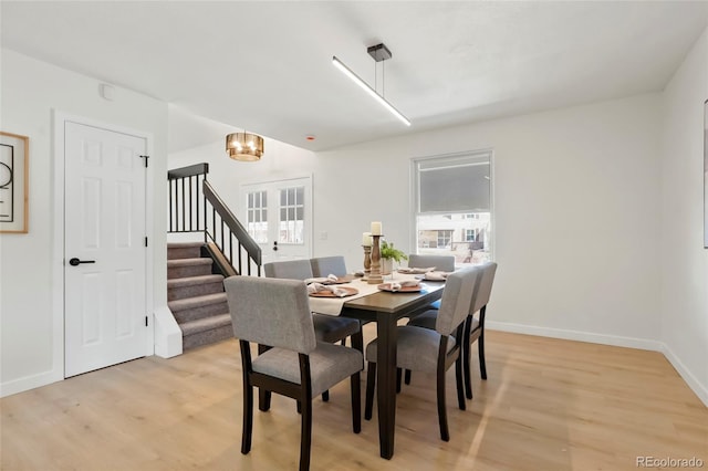 dining room featuring baseboards, an inviting chandelier, stairs, and light wood finished floors