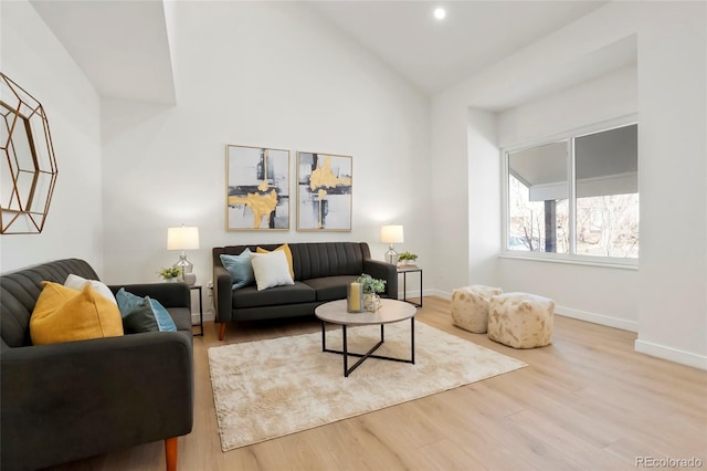 living room featuring wood finished floors, baseboards, and high vaulted ceiling