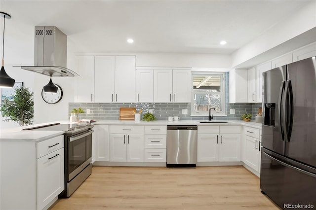 kitchen with light countertops, a peninsula, exhaust hood, stainless steel appliances, and a sink