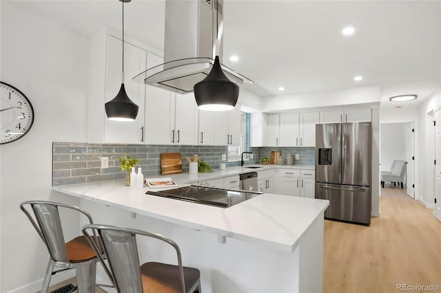 kitchen with island exhaust hood, a sink, white cabinetry, appliances with stainless steel finishes, and a peninsula