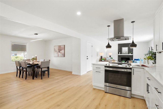 kitchen with a peninsula, white cabinets, island range hood, and stainless steel range with electric cooktop