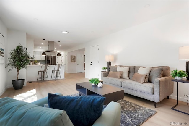 living room with recessed lighting, baseboards, and light wood-style floors