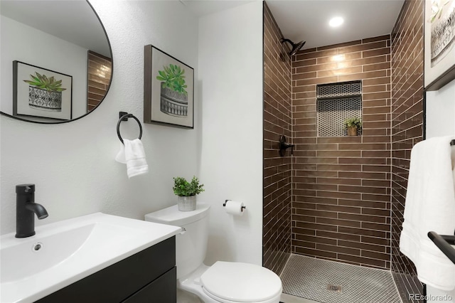 full bath featuring toilet, tiled shower, and vanity