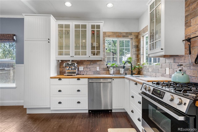 13349 Albion Cir, Thornton, CO 80241 - kitchen featuring appliances with stainless steel finishes, tasteful backsplash, butcher block countertops, glass insert cabinets, and recessed lighting