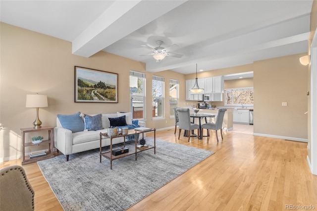 living room featuring beamed ceiling, ceiling fan, and light hardwood / wood-style flooring