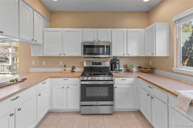 kitchen with white cabinets, light tile patterned floors, and appliances with stainless steel finishes