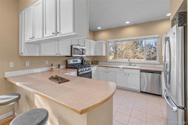 kitchen with white cabinets, a kitchen breakfast bar, sink, appliances with stainless steel finishes, and kitchen peninsula