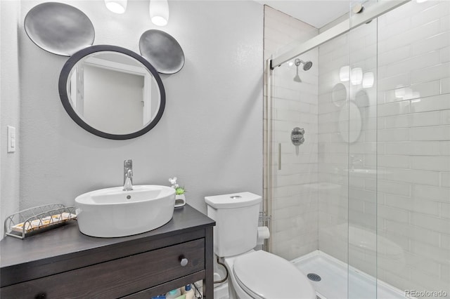 bathroom with toilet, a shower with shower door, and sink