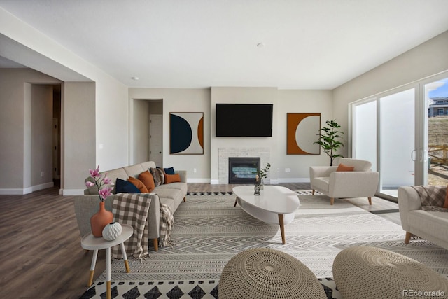 living area with a glass covered fireplace, baseboards, and wood finished floors